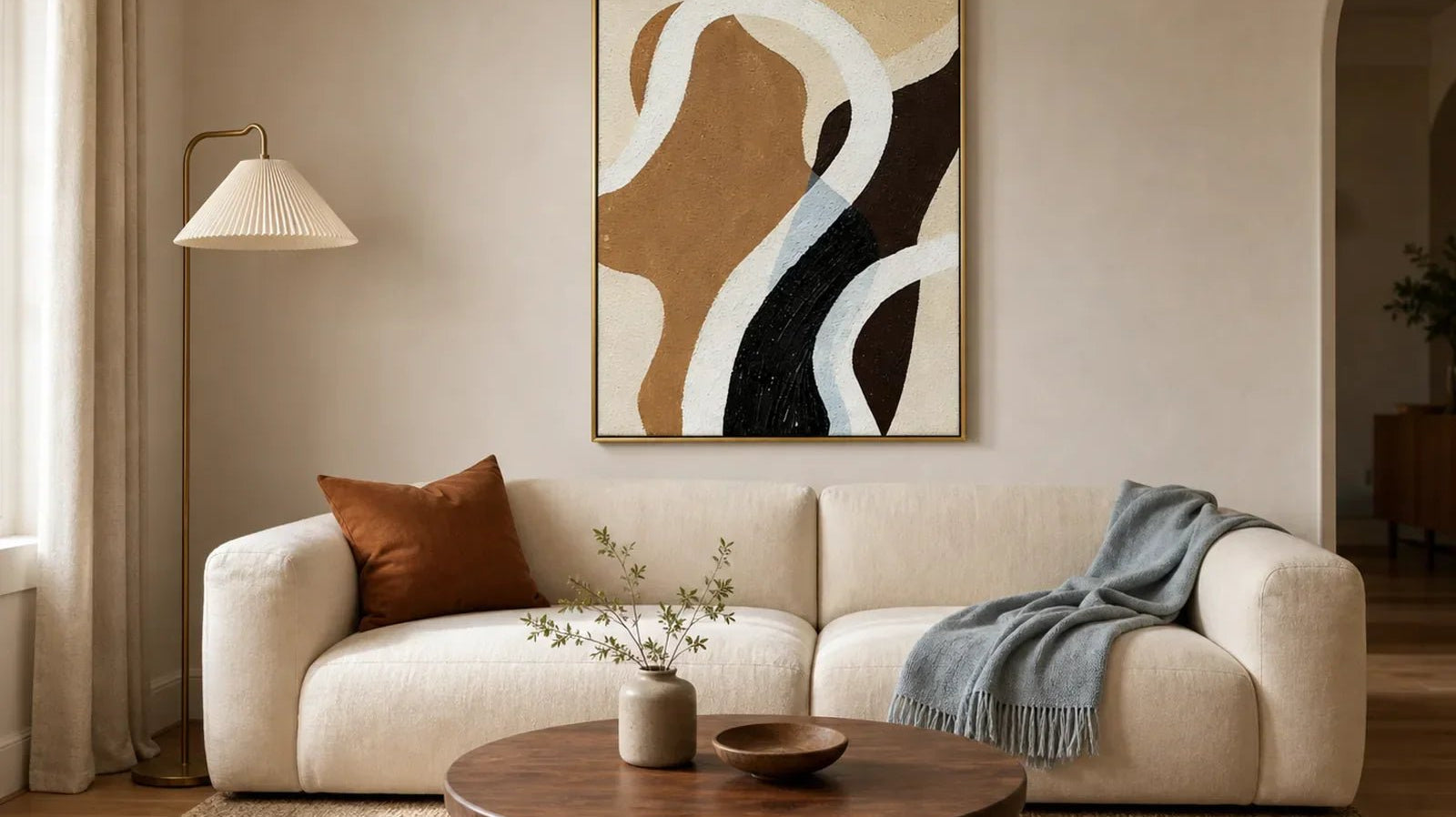 Hand-painted earth-tone abstract wall art with flowing curves above a cream sofa in an organic modern living room