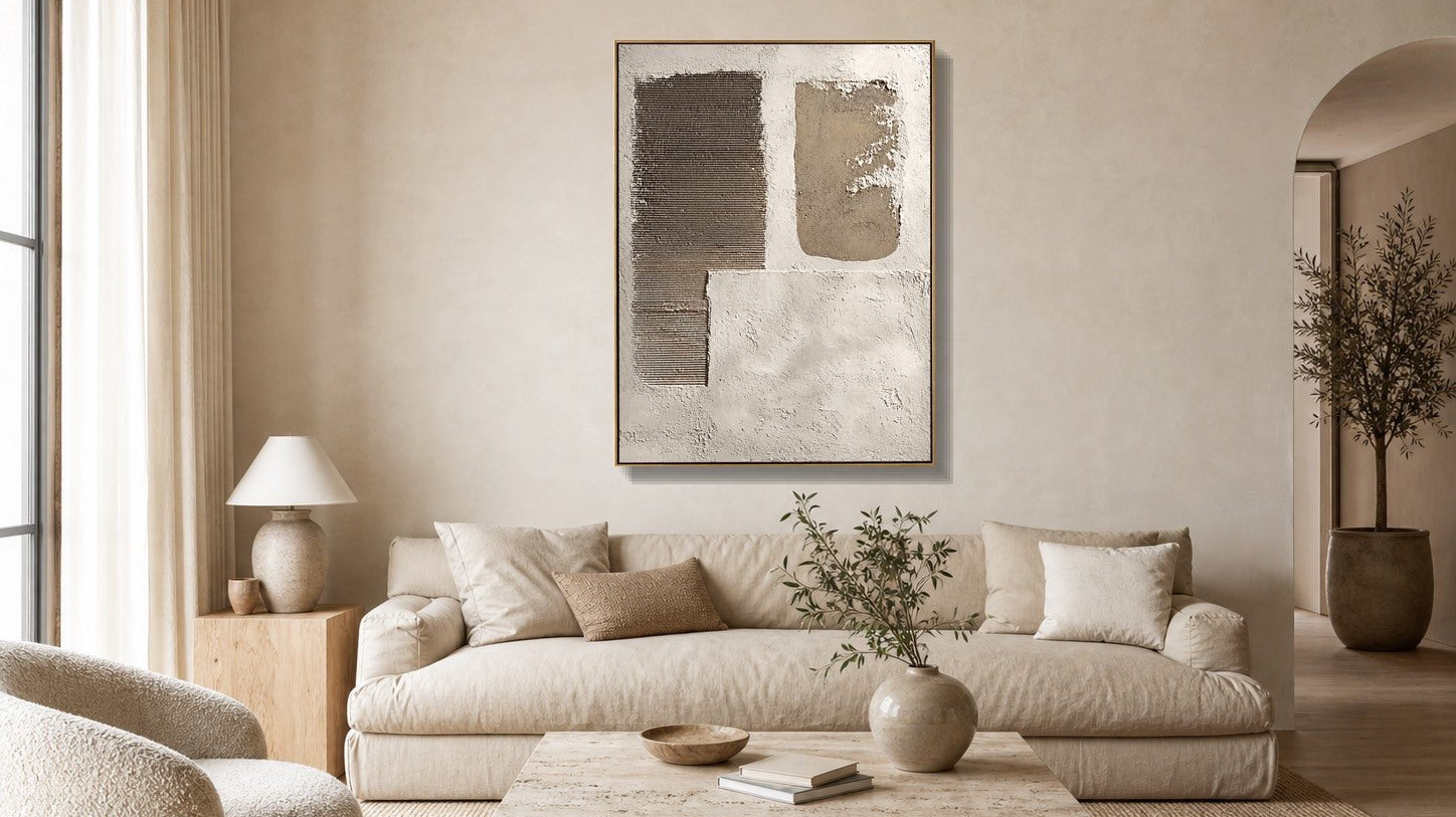 Neutral textured geometric wall art above a beige sofa in a warm minimalist living room
