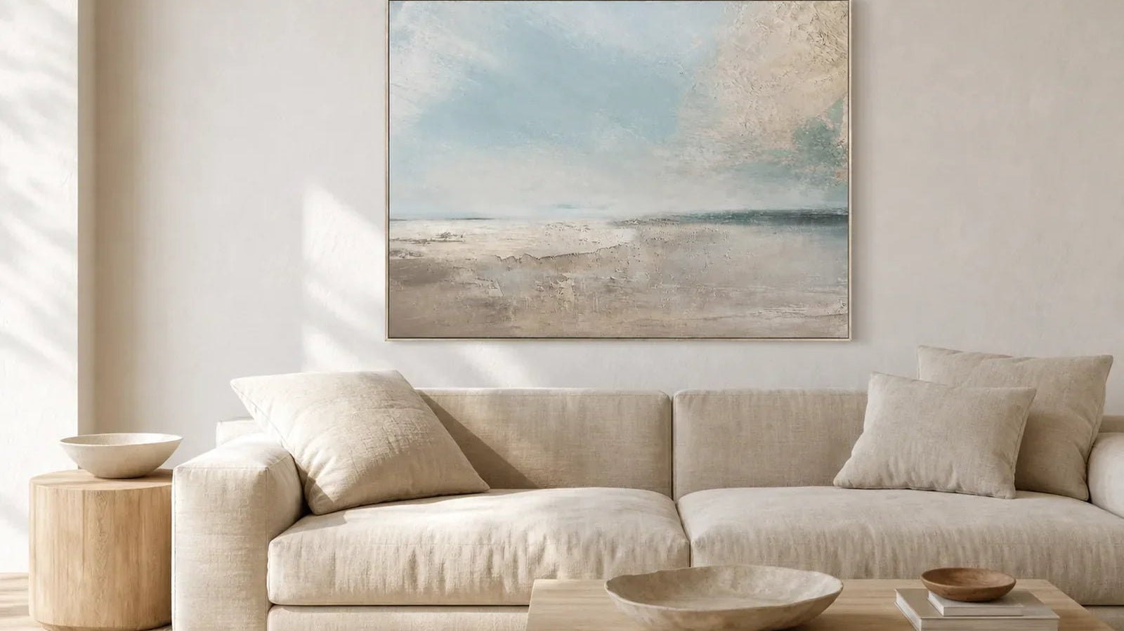 Hand-painted pale blue seascape wall art above a neutral linen sofa in a quiet living room