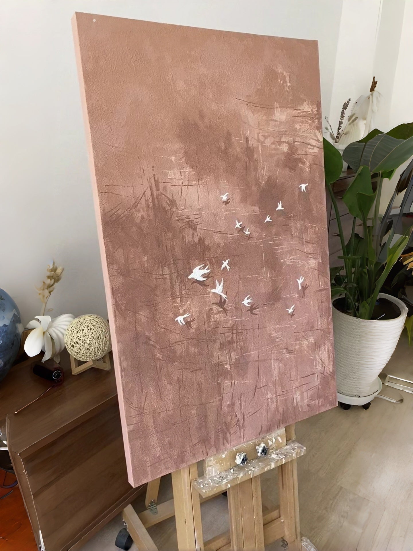 Hand-painted abstract bird wall art featuring white birds in flight over a textured blush pink and taupe background, contemporary canvas artwork for modern living room and bedroom decor.