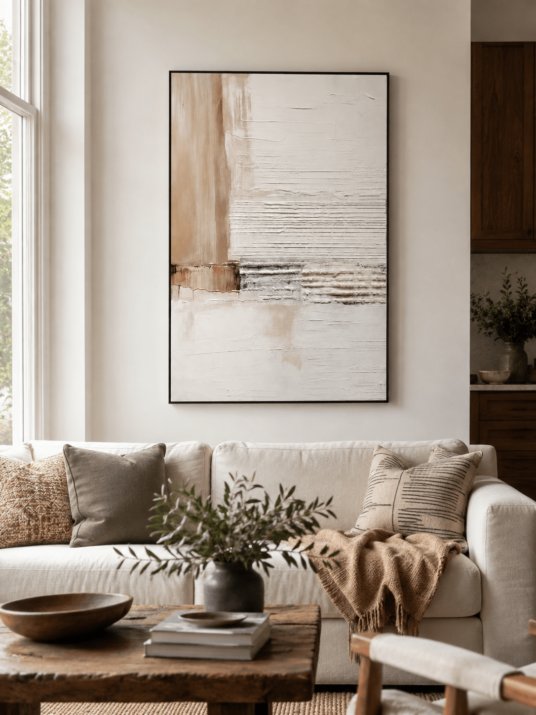 Neutral textured abstract painting displayed above a beige sofa in an organic modern living room