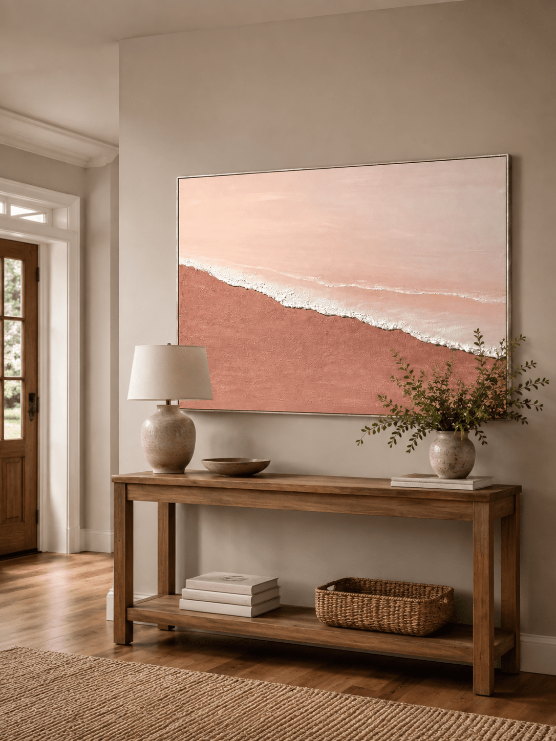 Minimalist blush pink beach painting displayed above a wood console in a modern neutral entryway