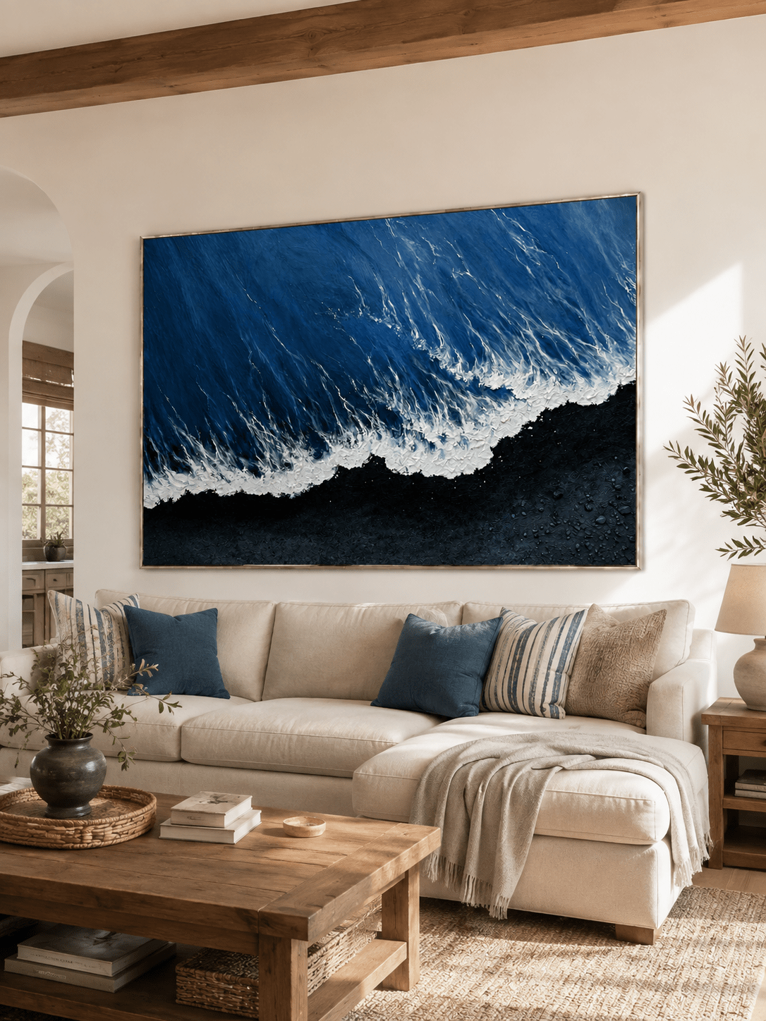 Blue and black textured ocean wave painting displayed above a neutral sofa in a modern living room