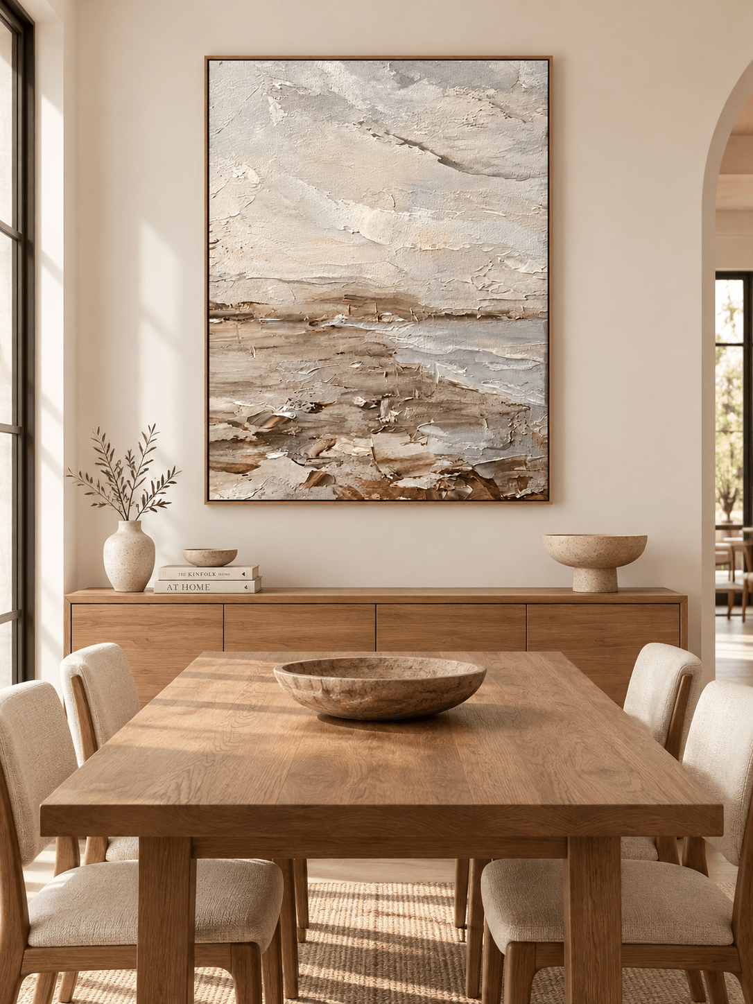 Vertical neutral coastal landscape wall art displayed in an open dining room with natural wood and stone furniture