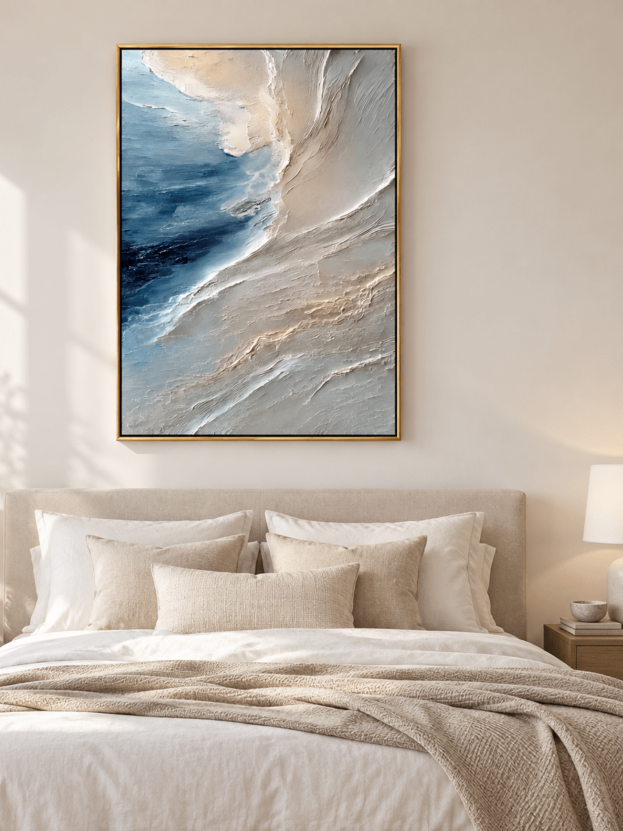 Deep blue abstract seascape painting displayed above a bed in a calming modern coastal bedroom