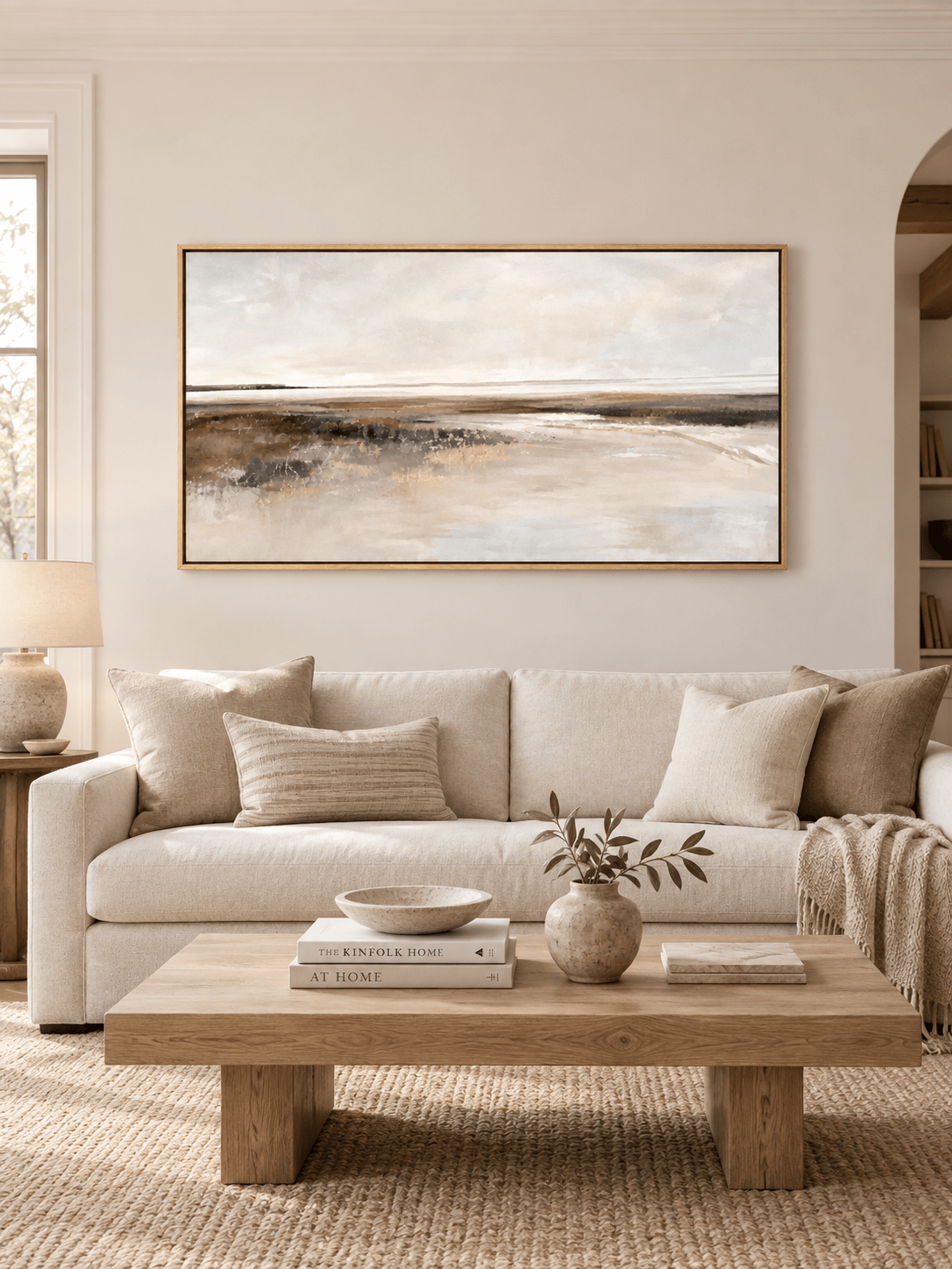 Large panoramic neutral coastal landscape painting displayed above a sofa in a modern organic living room