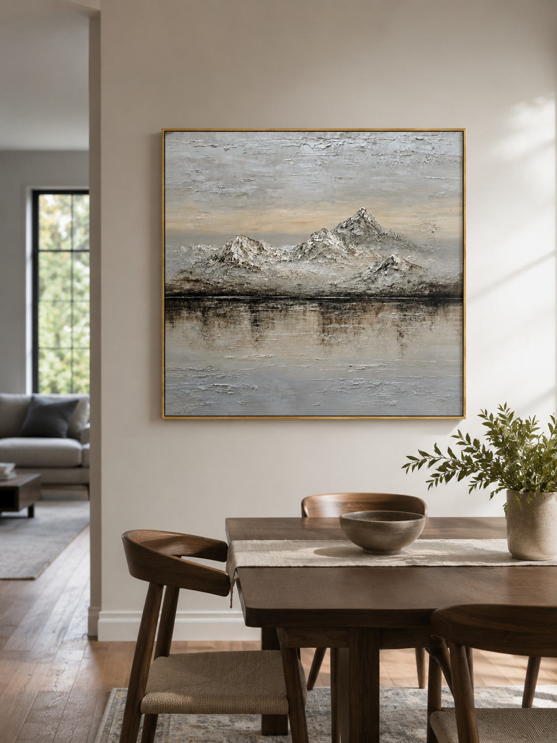 Textured neutral mountain lake painting displayed in a warm open-plan dining room