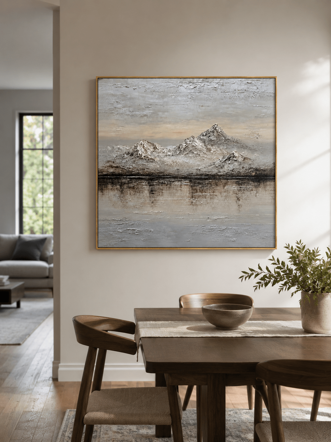Textured neutral mountain lake painting displayed in a warm open-plan dining room