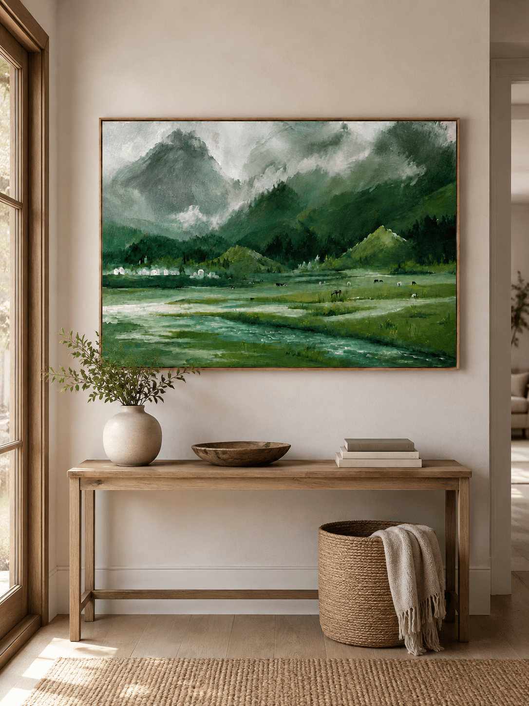 Horizontal alpine landscape painting displayed above a long wood console in a modern entryway