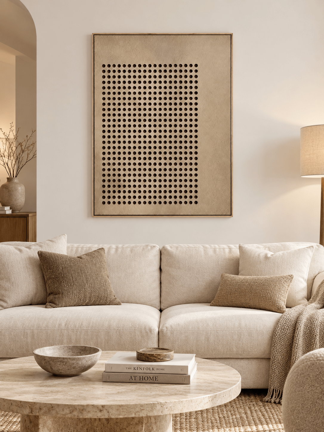 Large beige geometric dot painting displayed above a sofa in a minimalist contemporary living room
