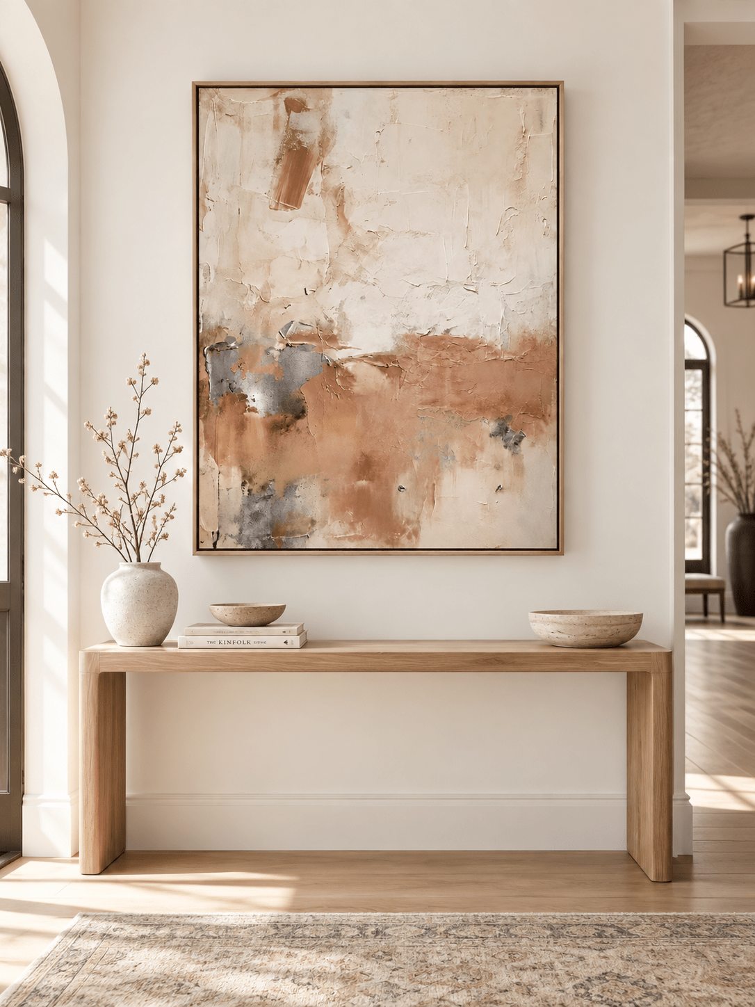 Vertical blush beige abstract painting displayed above a console in a modern organic entryway