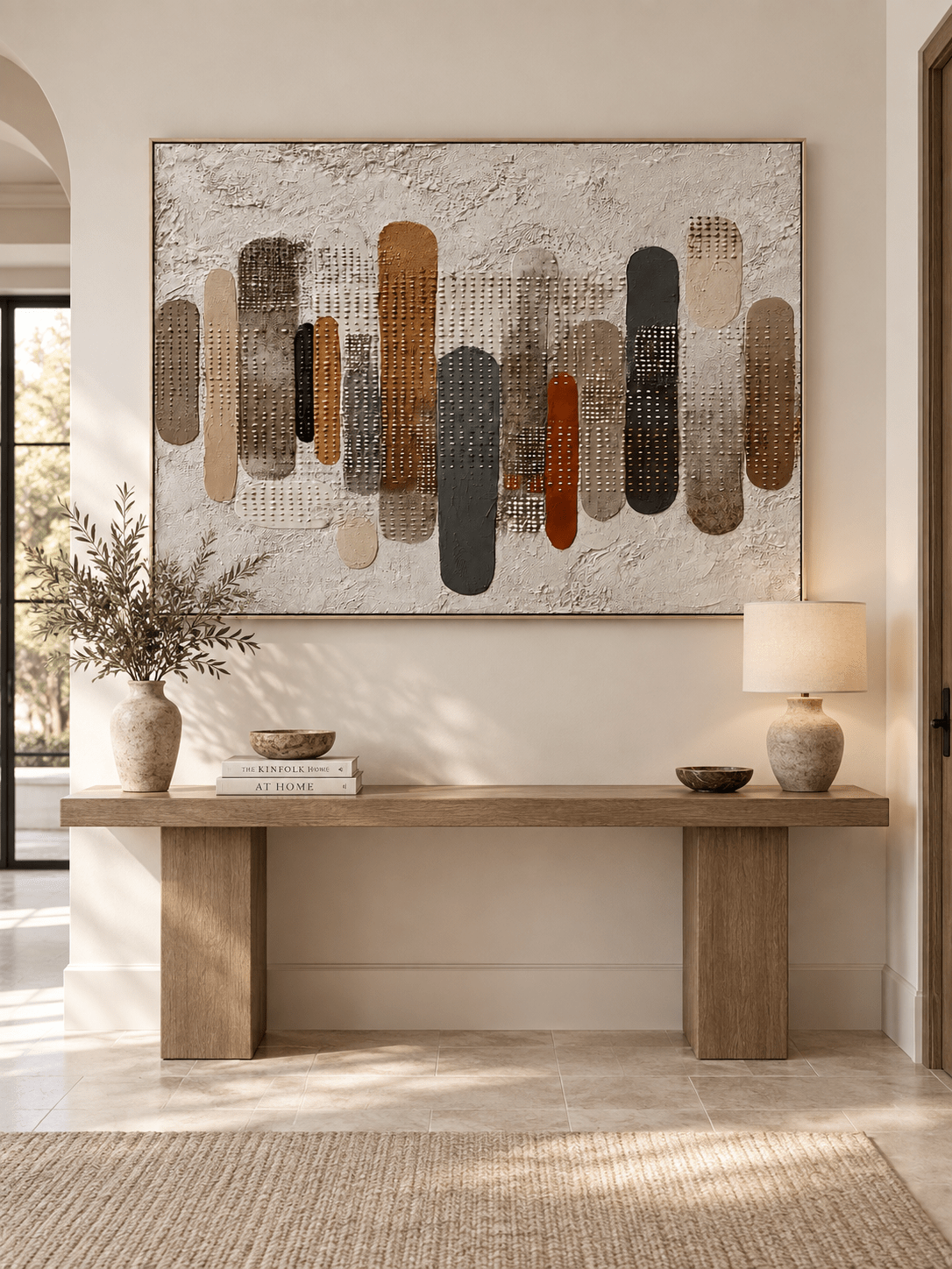 Horizontal textured earth-tone abstract painting displayed above a console in a contemporary entryway
