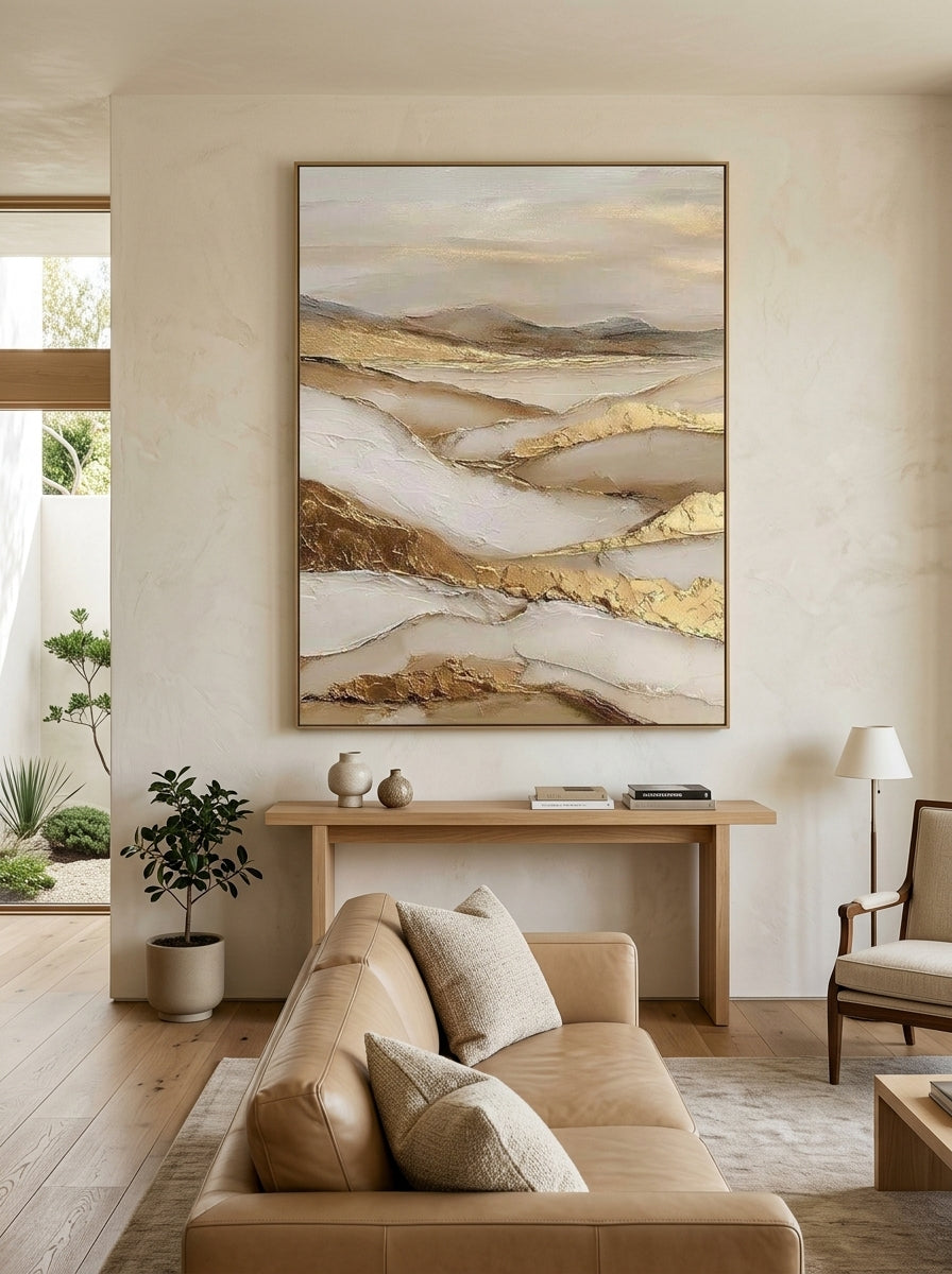 Vertical textured desert dune landscape painting with gold leaf above a warm modern living room couch