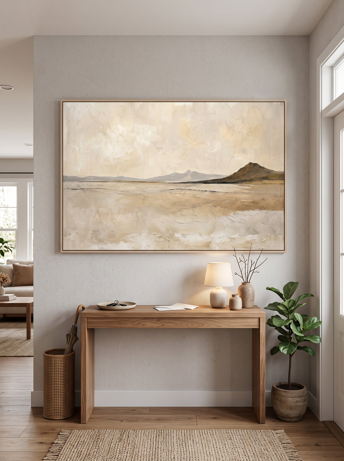 Framed textured desert mountain landscape painting styled above a wooden console table in a bright modern entryway