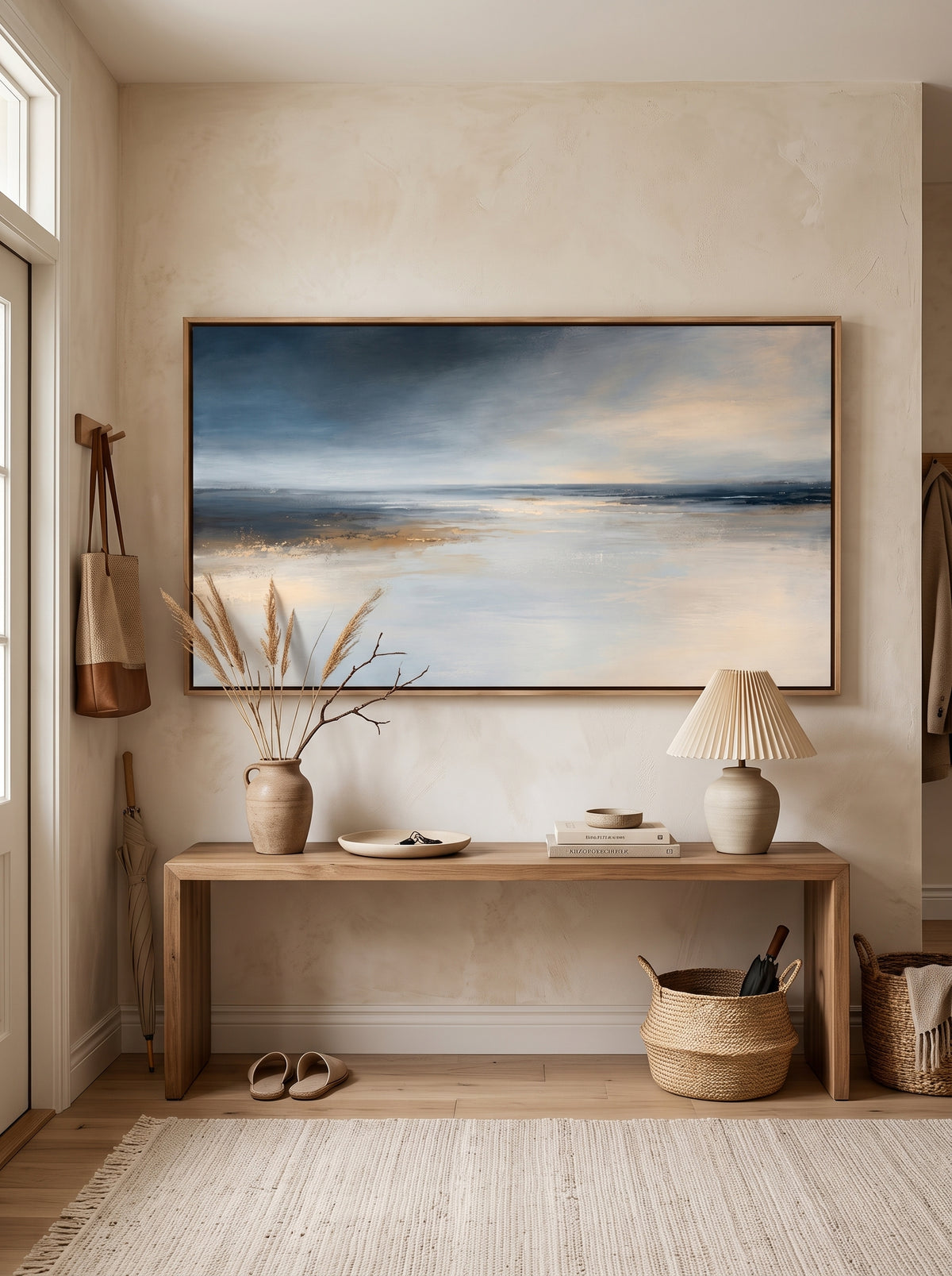 Atmospheric indigo blue coastal horizon canvas painting mounted above minimalist console table in entryway