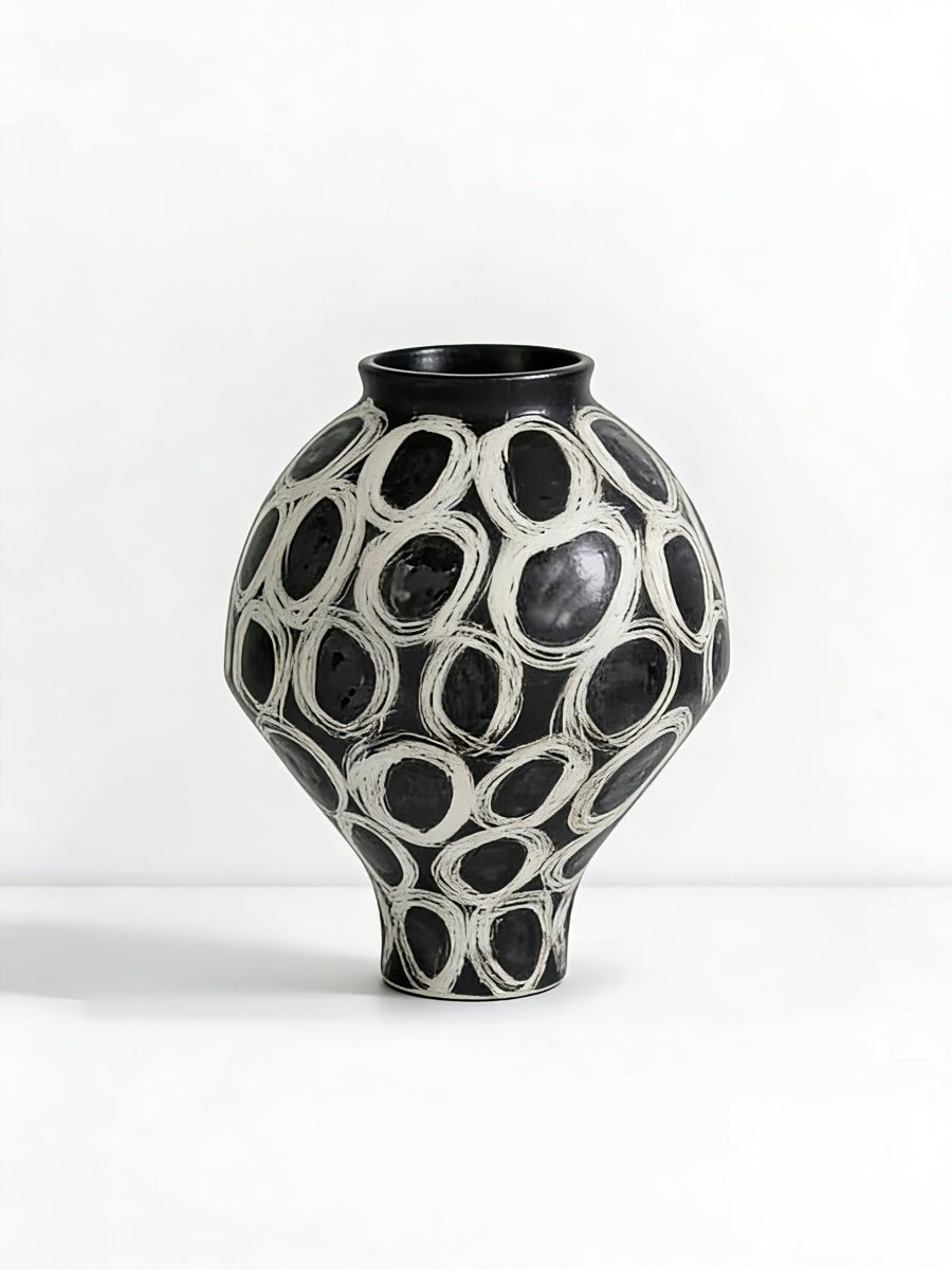 hand-painted black and white abstract ceramic vase with circular patterns, contemporary sculptural vase on a minimalist console.