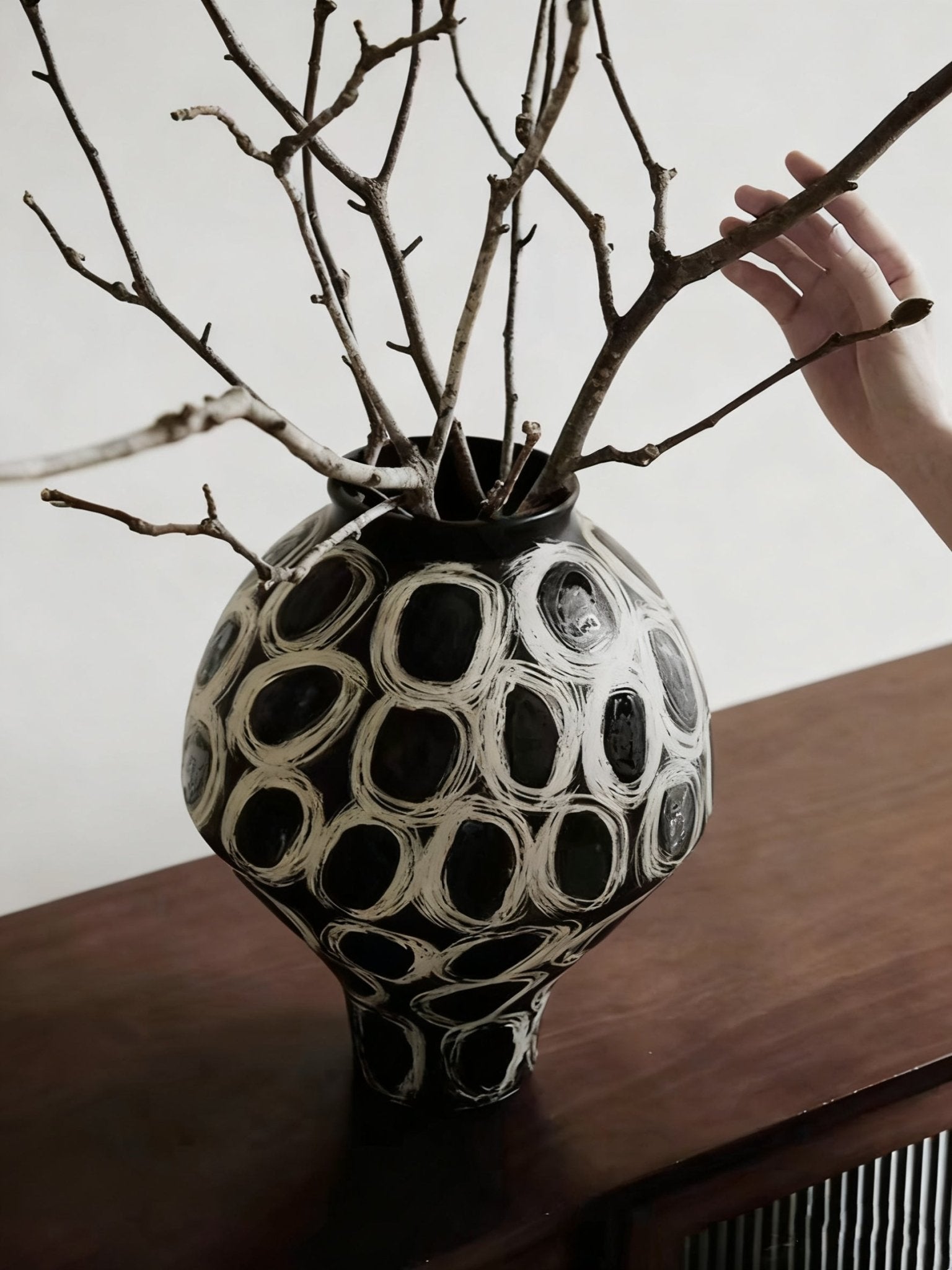 hand-painted black and white abstract ceramic vase with circular patterns, contemporary sculptural vase on a minimalist console.