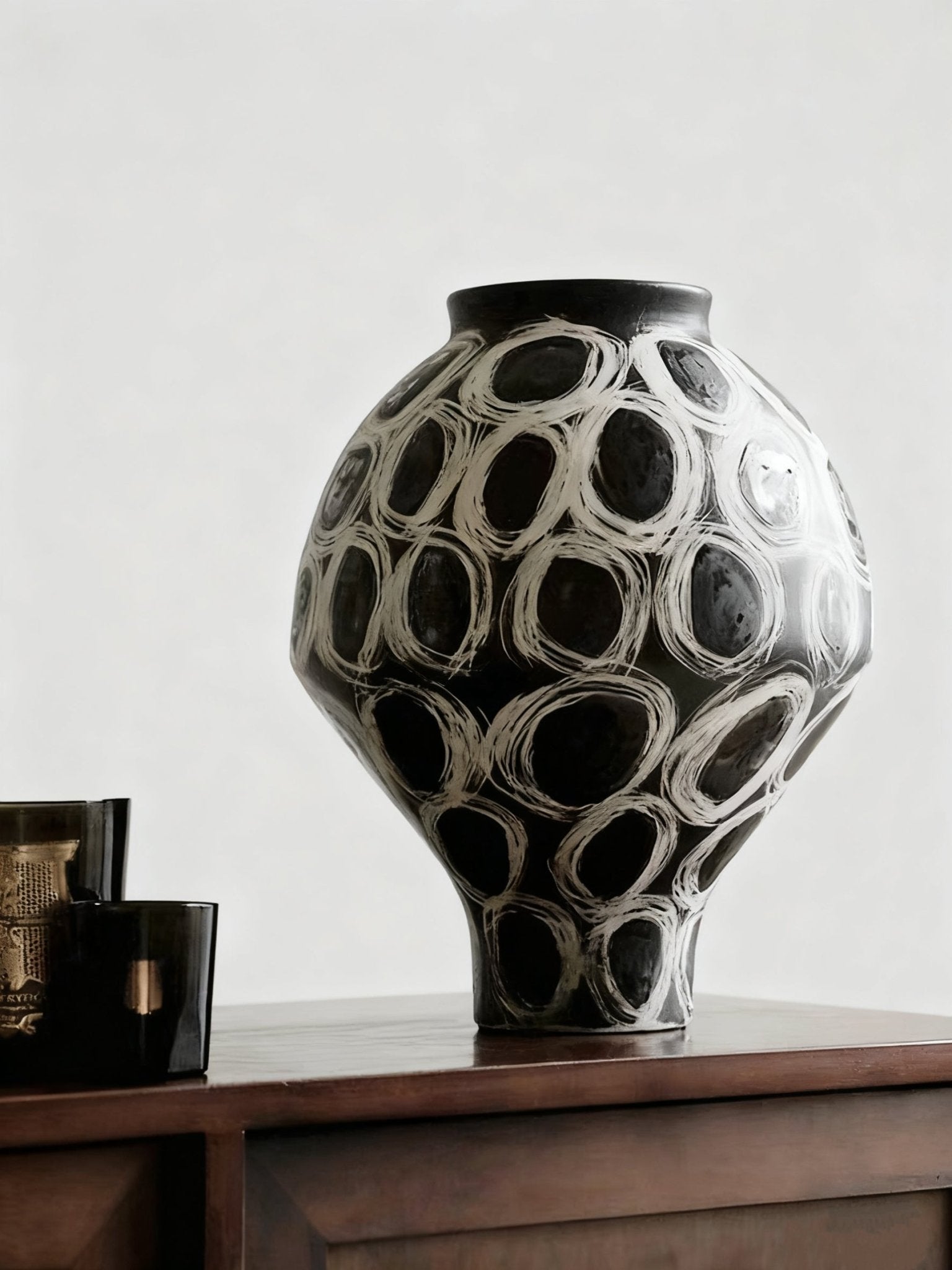 hand-painted black and white abstract ceramic vase with circular patterns, contemporary sculptural vase on a minimalist console.