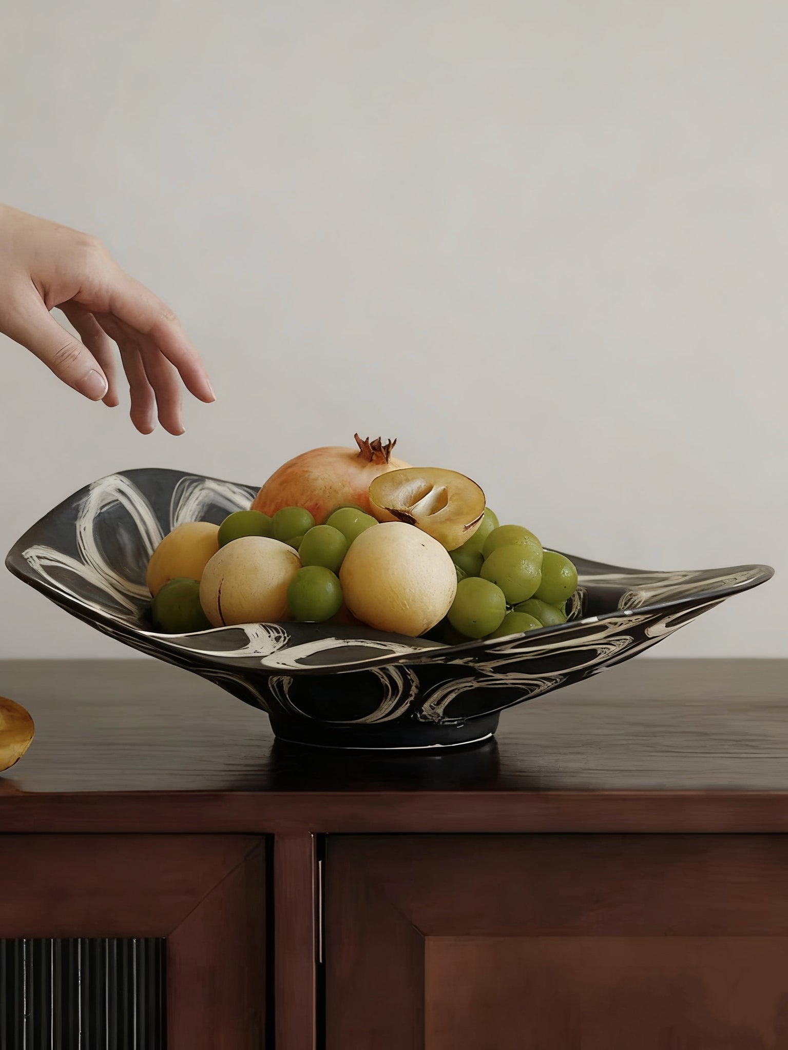 abstract black and white ceramic bowl with organic wavy edges and hand-painted circular patterns on a white console.