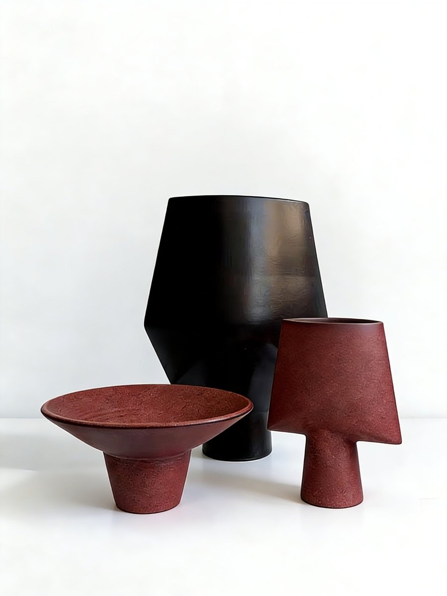artisan ceramic geometric sculptures in matte rust red and black, modern minimalist architectural home decor on a white background.