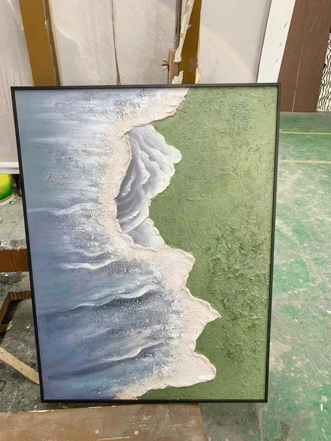 Side view of 3D hand-painted textured painting showing thick white seafoam between moss green meadow and slate blue ocean.