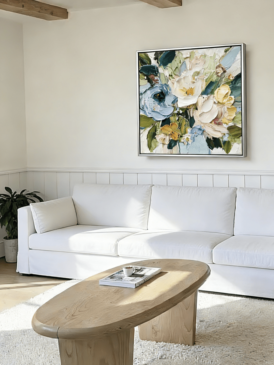 Large square 3D textured floral painting showing heavy impasto green and white flowers in a modern bright living room.