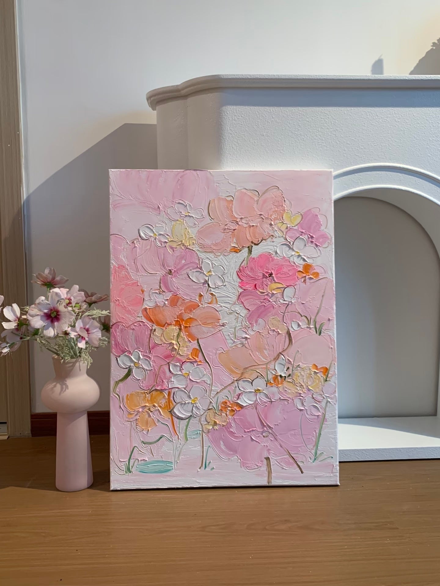 Hand painted pink floral canvas styled beside a white fireplace