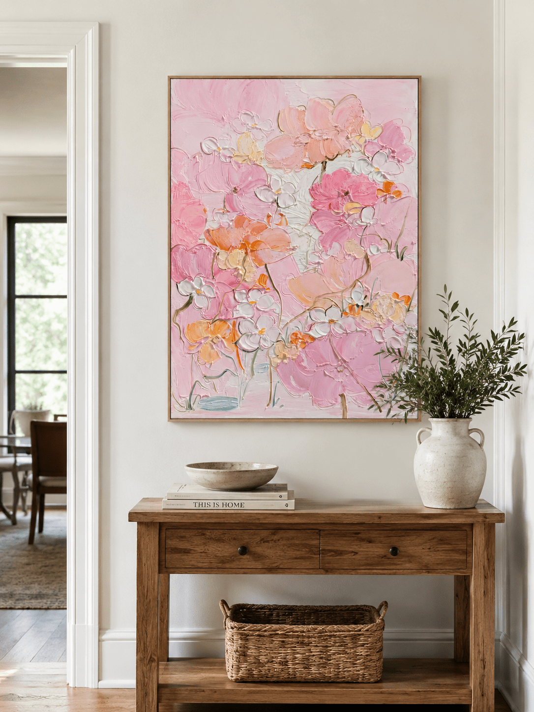 Blush floral wall art above a wood console in a bright entryway