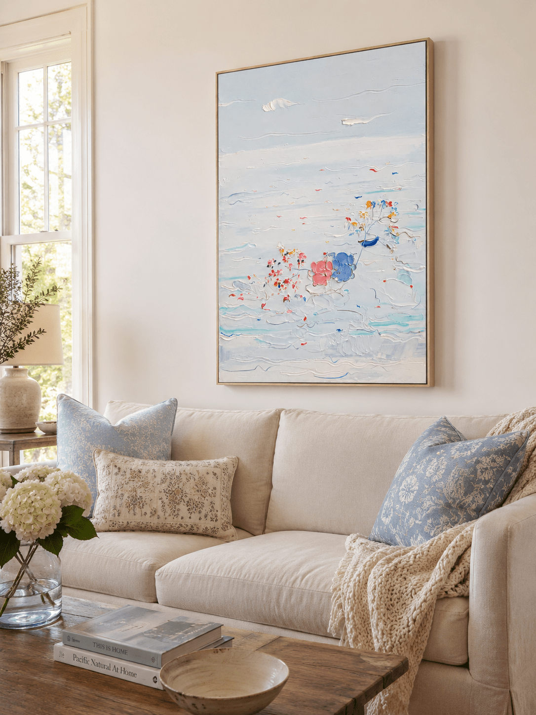 Textured coastal canvas displayed above a cream living room sofa