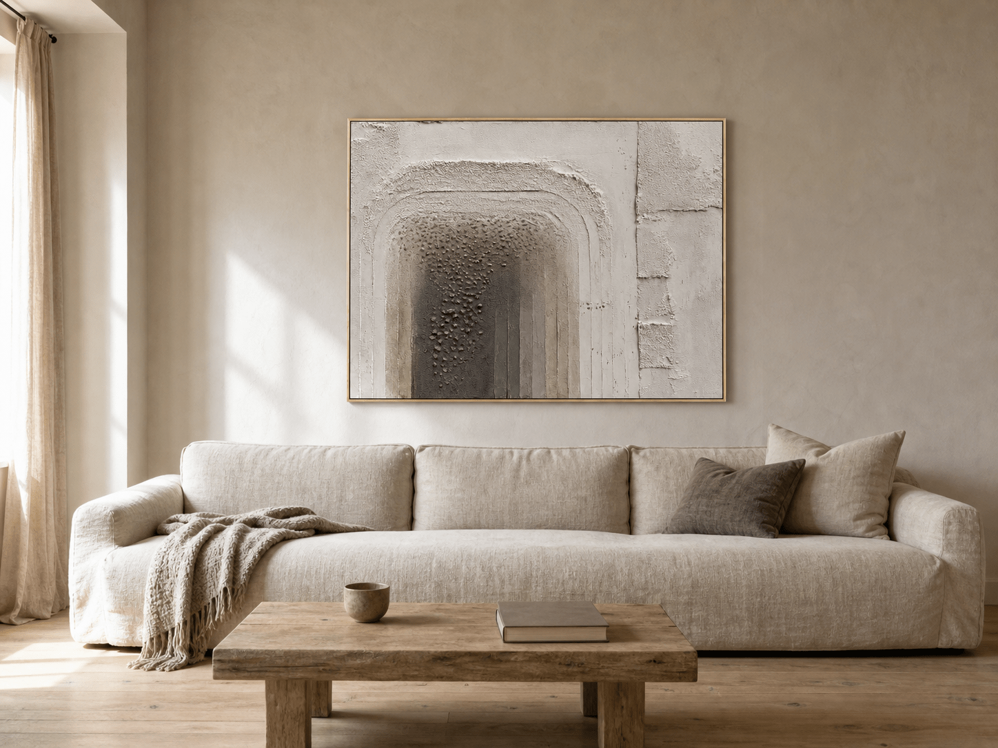 3D textured wall art with a neutral architectural relief above an oatmeal sofa in a naturally lit living room