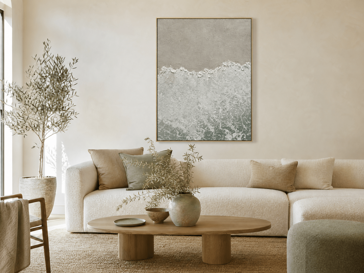 Textured beach wall art with white surf and sage water above a cream sofa