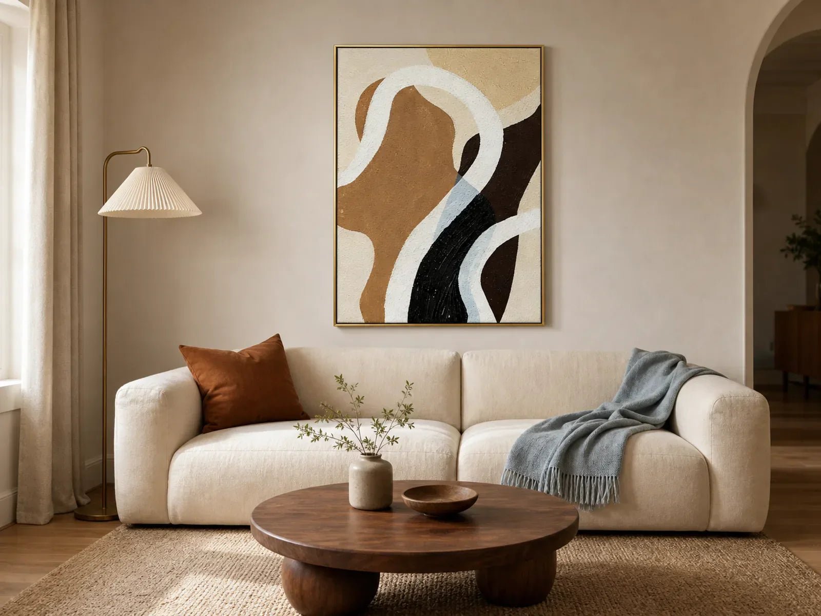 Hand-painted earth-tone abstract wall art with flowing curves above a cream sofa in an organic modern living room