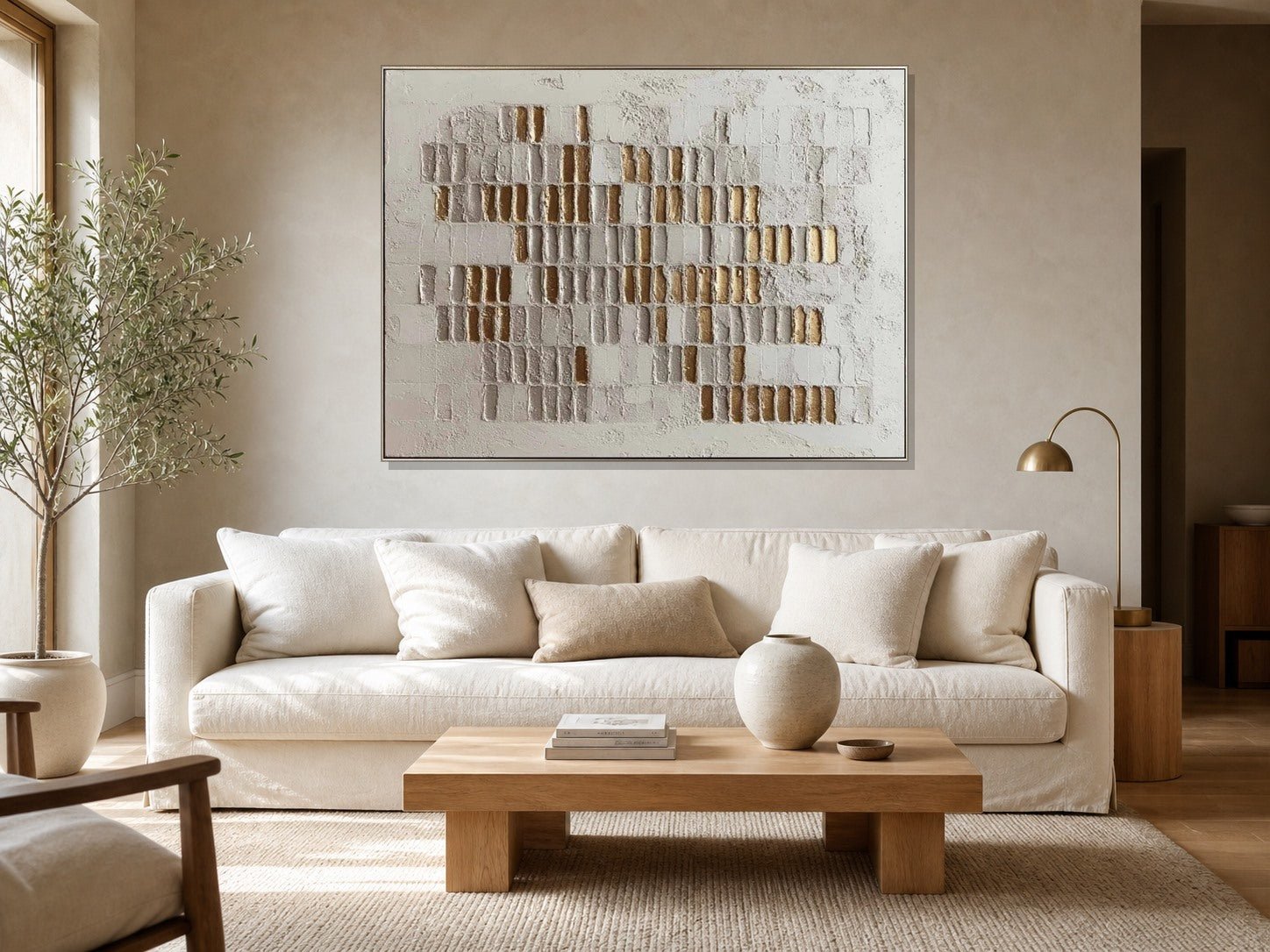 White and gold textured wall art above an ivory sofa in a warm neutral living room