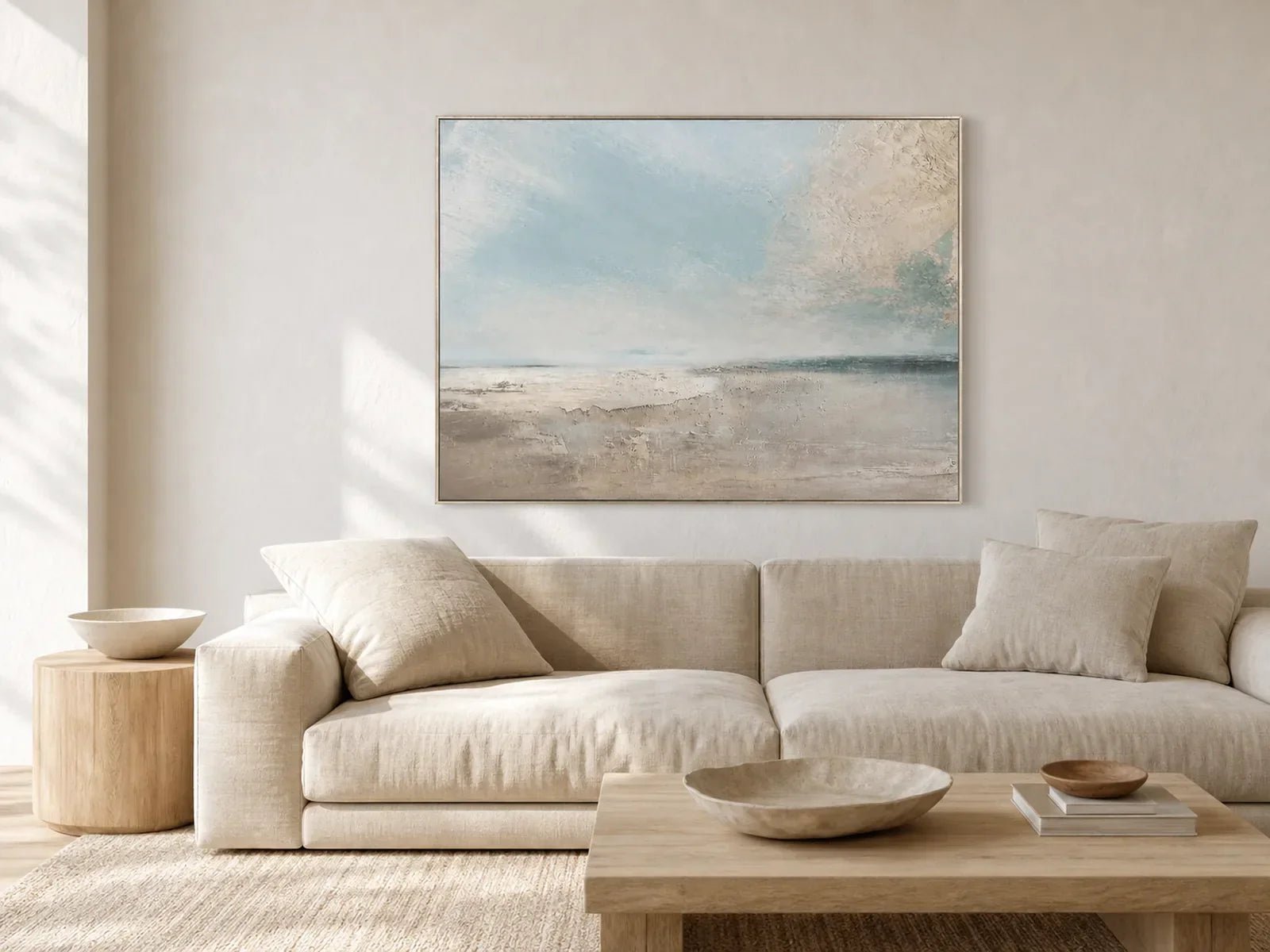Hand-painted pale blue seascape wall art above a neutral linen sofa in a quiet living room
