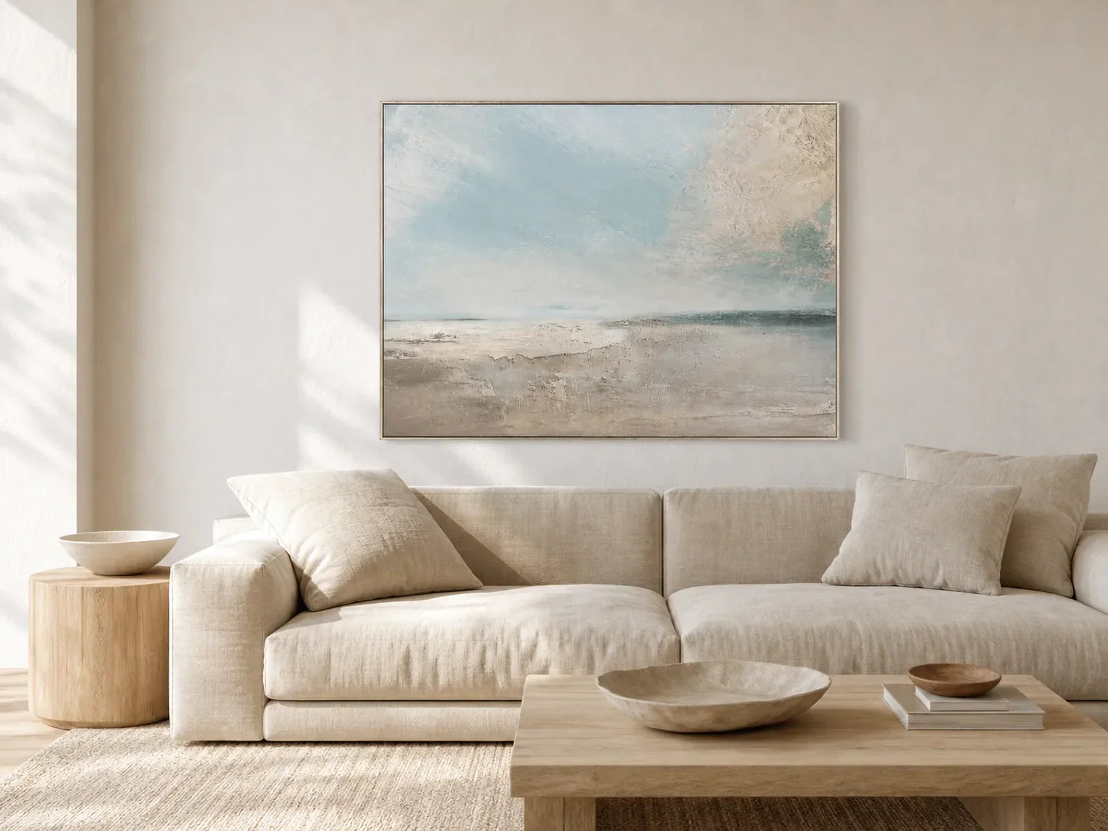 Hand-painted pale blue seascape wall art above a neutral linen sofa in a quiet living room