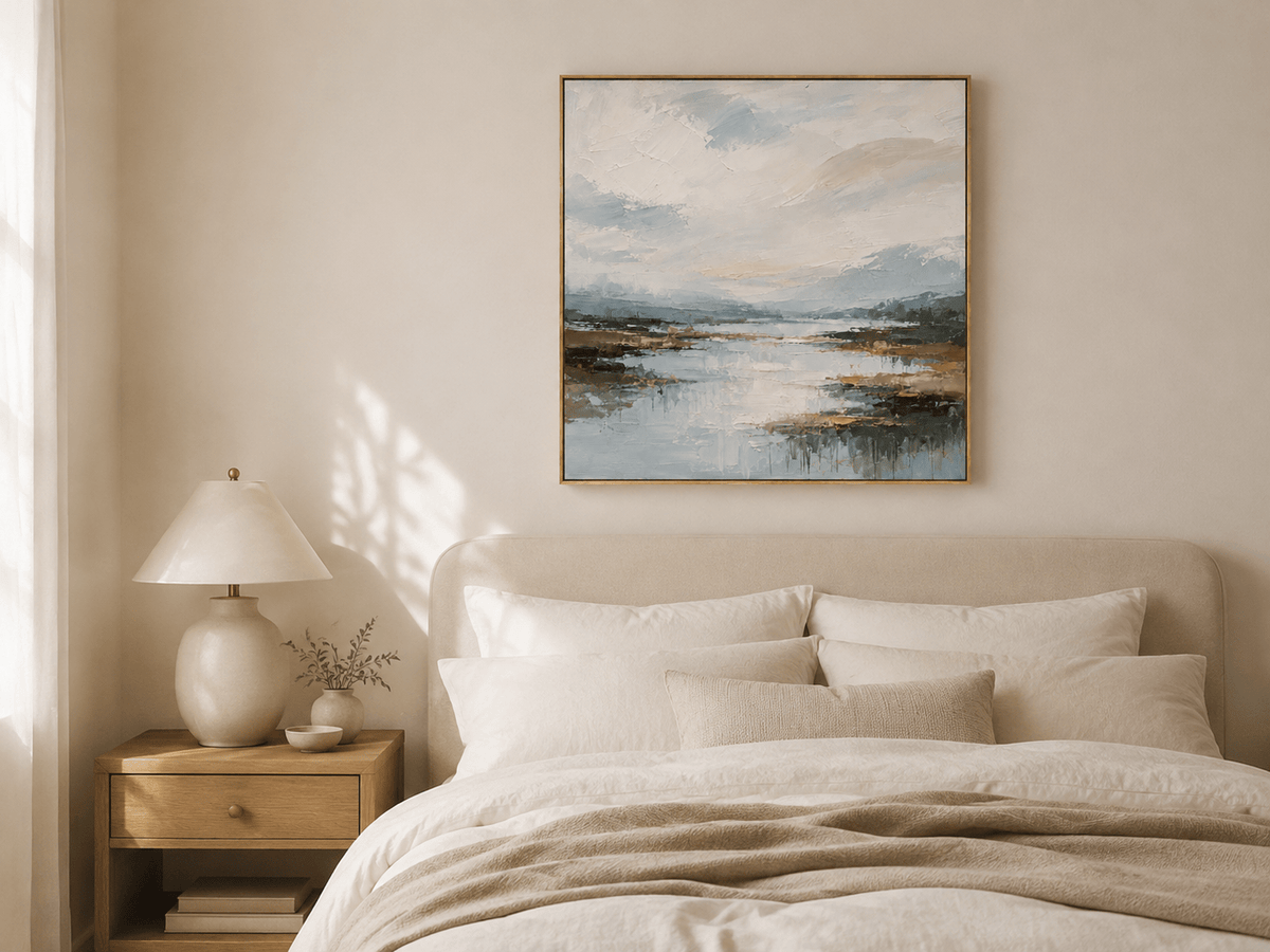 Blue-gray mountain river painting displayed above a warm neutral upholstered bed