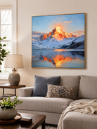 Mountain sunrise painting above a neutral sofa in a contemporary living room with warm wood accents
