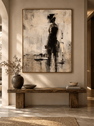 Minimalist woman in black wall art displayed in a refined entryway with beige, black and natural wood accents.