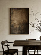 Close-up of vertical hand-painted 3D textured abstract painting with amber, brown, and charcoal impasto layers by Akari Kobayashi in a gold frame.