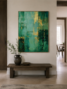 Vertical emerald green abstract painting displayed above a wood console in an organic modern entryway
