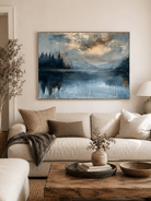 Hand-painted misty blue lake landscape wall art with mountains and gold accents displayed above a living room sofa