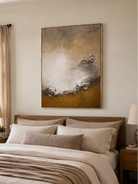 Ivory and brown textured shoreline painting displayed above the bed in a warm neutral bedroom