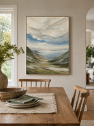 Impasto mountain lake painting displayed in a warm open-plan dining room