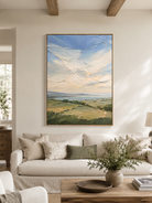 Sage green landscape painting above a cream sofa in an organic modern living room