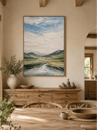 Hand-painted mountain valley wall art displayed in a modern open-plan dining room with neutral natural decor