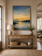 Golden sunset coastal painting displayed above a wood console in a modern organic entryway