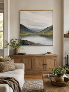Textured sage green mountain lake painting by Evelyn Li displayed above a neutral sofa in a modern living room