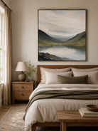 Calm mountain lake landscape wall art displayed above the bed in a neutral organic modern bedroom