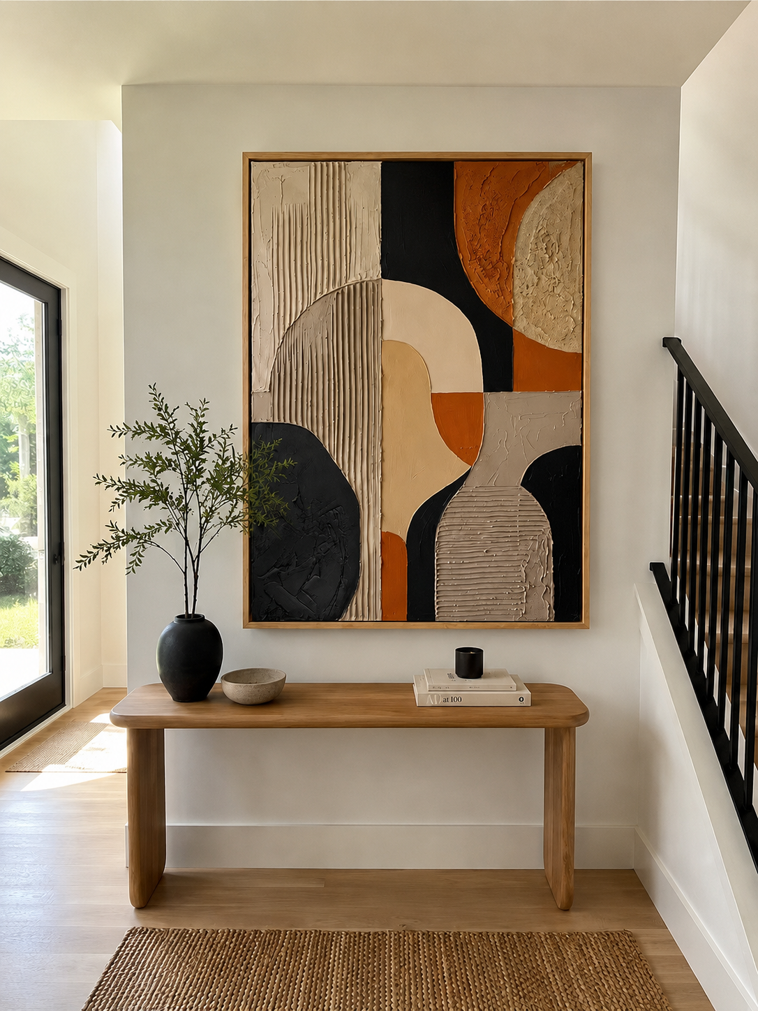 Terracotta and black abstract painting displayed above a wood console in an organic modern entryway