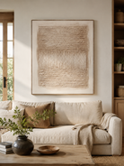 Neutral textured abstract painting displayed above a beige sofa in an organic modern living room